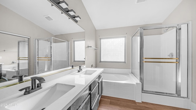 bathroom with lofted ceiling, wood finished floors, a stall shower, a bath, and double vanity