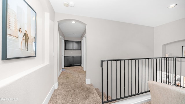 hallway featuring carpet, arched walkways, baseboards, and recessed lighting