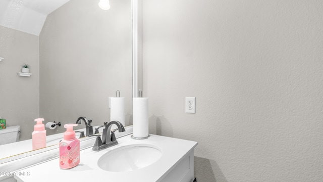 bathroom featuring vanity, toilet, and lofted ceiling