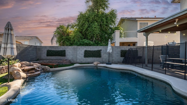 pool at dusk with a fenced backyard