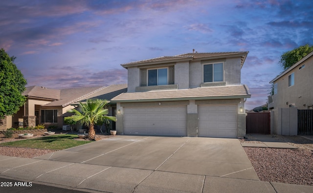 view of front of home with a tiled roof, stucco siding, concrete driveway, an attached garage, and fence