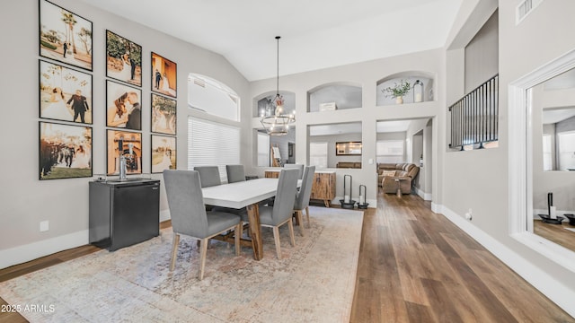 dining room with wood finished floors, a chandelier, baseboards, and lofted ceiling