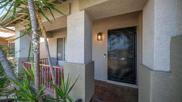 doorway to property with stucco siding and a porch