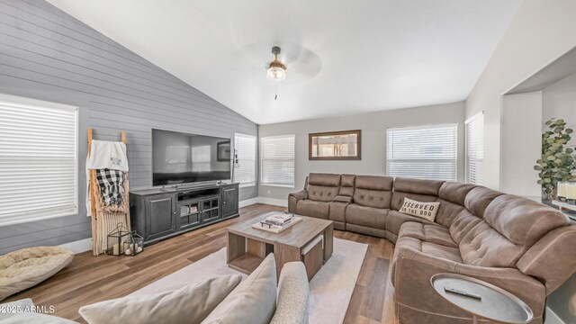 living area with lofted ceiling, ceiling fan, wood finished floors, wooden walls, and baseboards