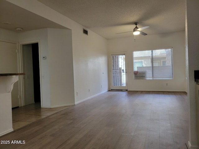 spare room featuring baseboards, visible vents, ceiling fan, wood finished floors, and a textured ceiling