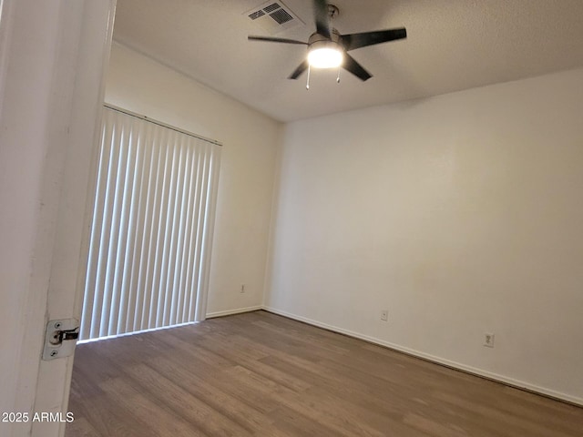 spare room featuring baseboards, ceiling fan, visible vents, and wood finished floors