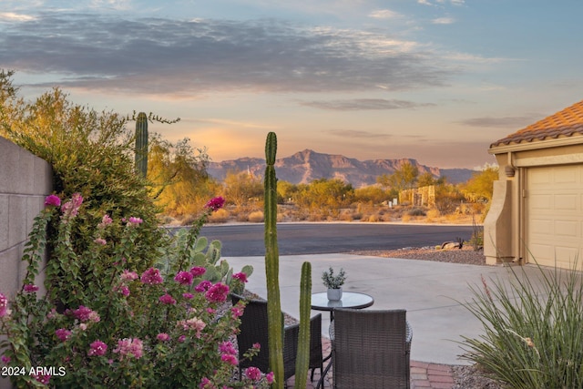 patio terrace at dusk featuring a mountain view and a garage