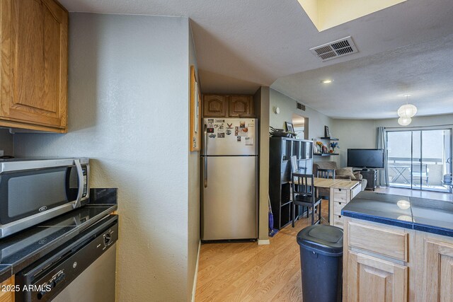 2228 N 52nd St Unit 213, Phoenix, AZ 85008 - kitchen featuring appliances with stainless steel finishes, light wood-style floors, dark countertops, open floor plan, and a textured ceiling