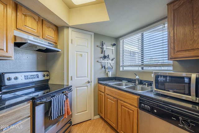 2228 N 52nd St Unit 213, Phoenix, AZ 85008 - kitchen with appliances with stainless steel finishes, a sink, under cabinet range hood, light wood-style floors, and dark countertops