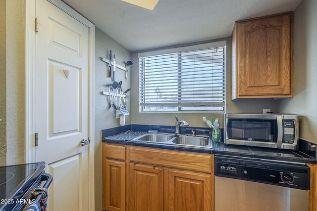 2228 N 52nd St Unit 213, Phoenix, AZ 85008 - kitchen featuring stainless steel appliances, a sink, dark countertops, brown cabinetry, and a textured wall