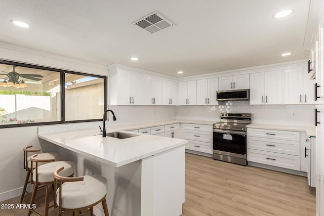 1611 W Palomino Dr, Chandler, AZ 85224 - kitchen with stainless steel appliances, a peninsula, white cabinets, backsplash, and a kitchen bar