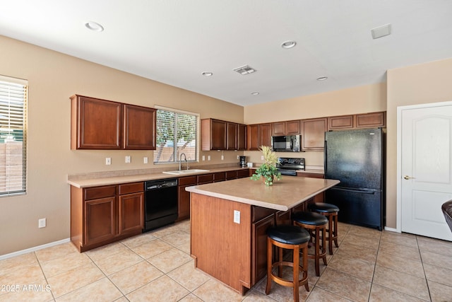 kitchen featuring a breakfast bar, a sink, visible vents, light countertops, and black appliances