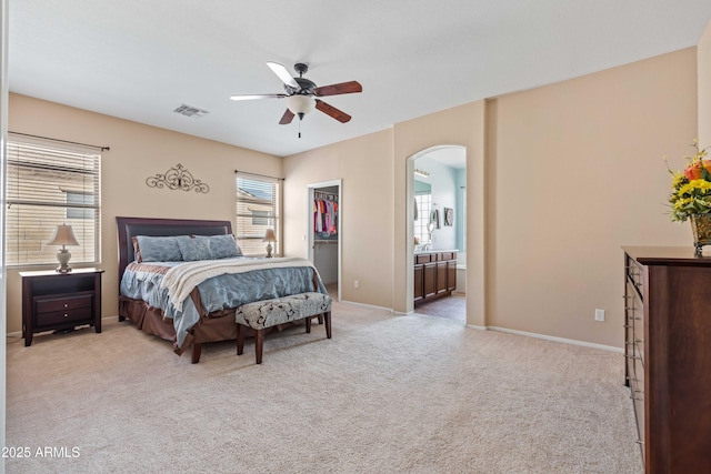 carpeted bedroom featuring visible vents, a spacious closet, arched walkways, and baseboards