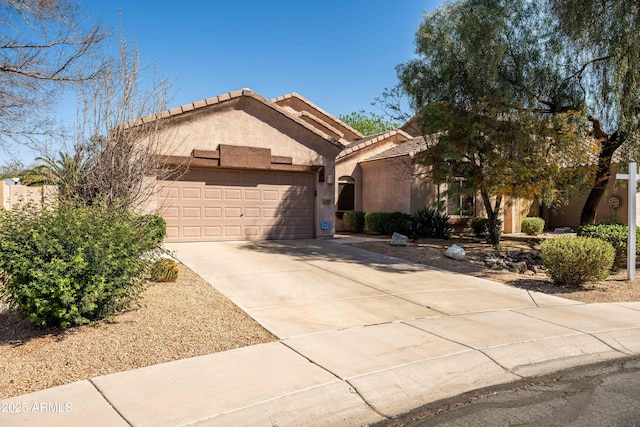 view of front of house featuring a garage, a tiled roof, concrete driveway, and stucco siding