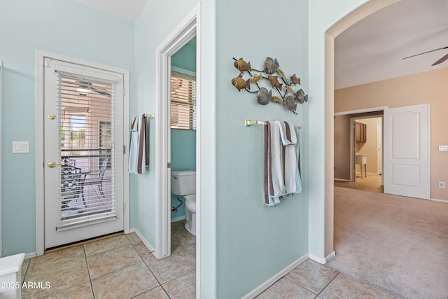 hall with light colored carpet, baseboards, and light tile patterned floors