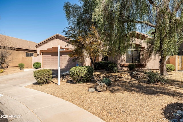 view of front of home with concrete driveway, a tiled roof, an attached garage, fence, and stucco siding