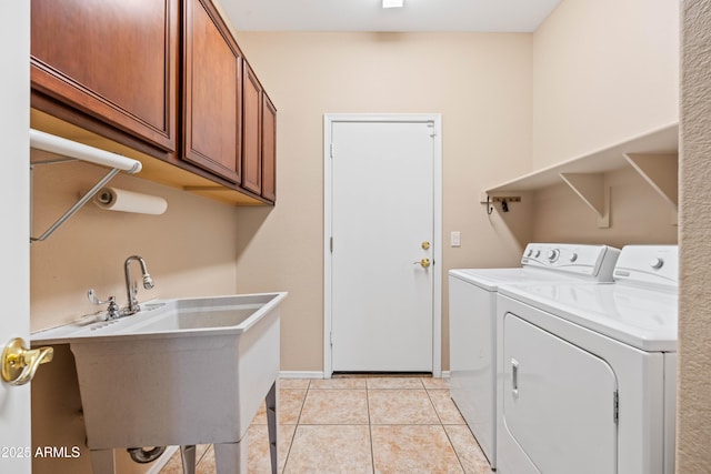 clothes washing area featuring washing machine and clothes dryer, light tile patterned floors, cabinet space, a sink, and baseboards