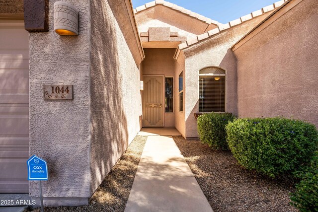 property entrance featuring a garage and stucco siding