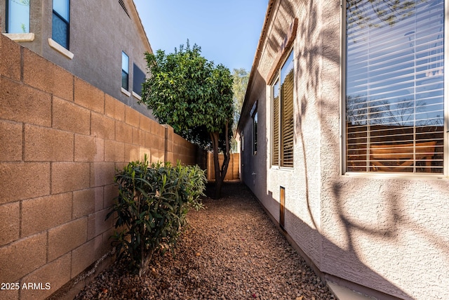 view of side of home featuring a fenced backyard and stucco siding