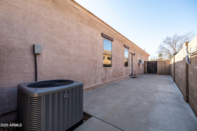 rear view of house with a patio, stucco siding, a gate, fence, and cooling unit