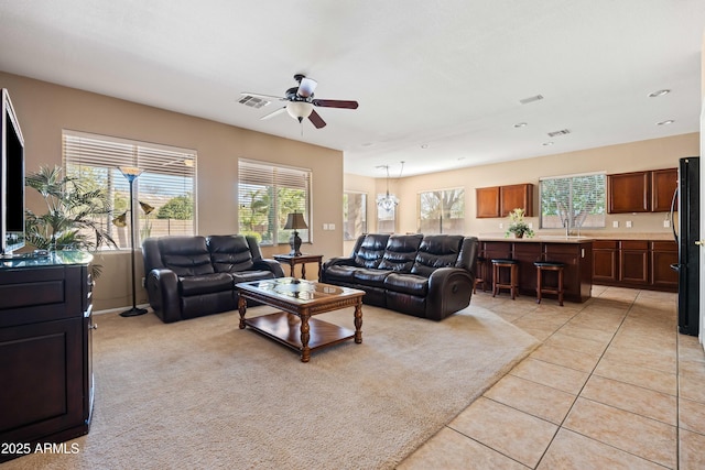 living area with light tile patterned floors, ceiling fan, a wealth of natural light, and visible vents