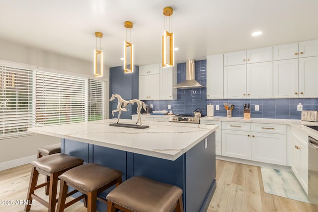 kitchen with light wood-style floors, a kitchen breakfast bar, wall chimney exhaust hood, tasteful backsplash, and a sink