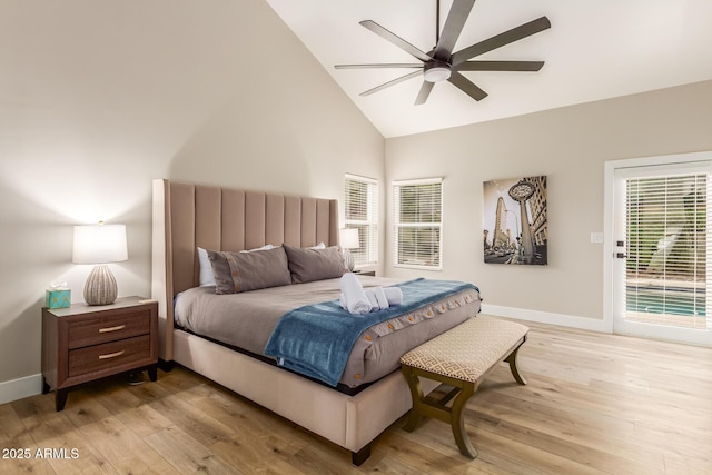 bedroom with high vaulted ceiling, multiple windows, light wood-style flooring, and access to exterior