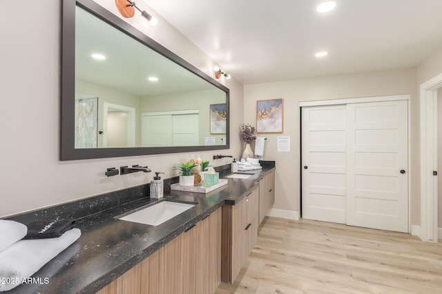 full bathroom featuring a sink, double vanity, recessed lighting, and wood finished floors