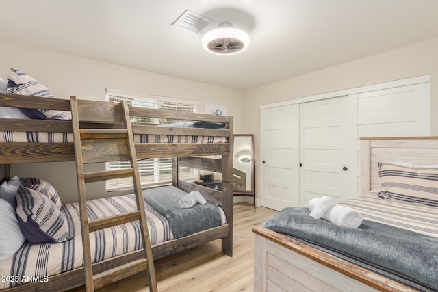 bedroom with visible vents, light wood-style floors, and a closet