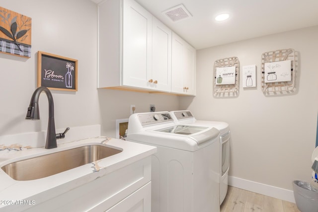 clothes washing area featuring visible vents, baseboards, washing machine and clothes dryer, a sink, and cabinet space