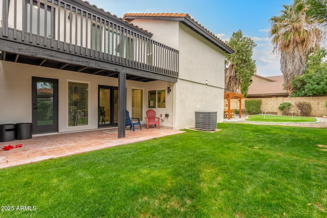 back of property featuring a tiled roof, central AC unit, stucco siding, and a yard