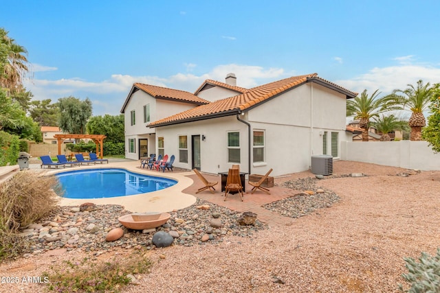 back of property with a tiled roof, a fenced backyard, a pergola, and a chimney