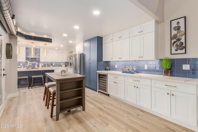 kitchen with stainless steel fridge with ice dispenser, wine cooler, wall chimney range hood, white cabinetry, and tasteful backsplash