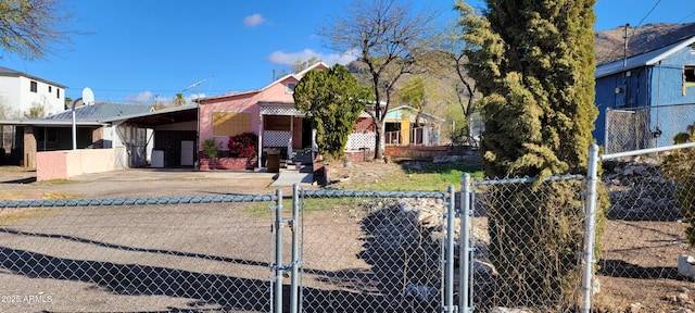 view of front facade featuring a carport, concrete driveway, a fenced front yard, and a gate