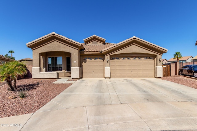 view of front of home with stucco siding, fence, concrete driveway, a garage, and a tiled roof