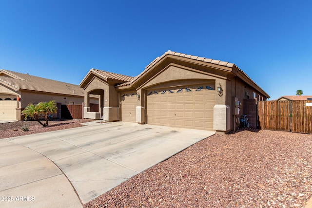 view of front of house featuring stucco siding, fence, concrete driveway, an attached garage, and a tiled roof