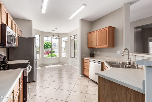 kitchen with appliances with stainless steel finishes, light countertops, decorative light fixtures, and a sink