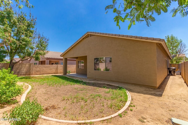 rear view of house featuring a fenced backyard, a patio, and stucco siding