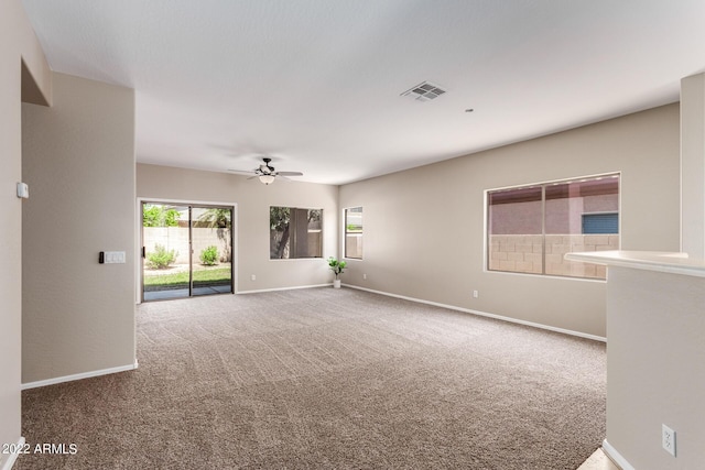 carpeted spare room featuring ceiling fan, visible vents, and baseboards