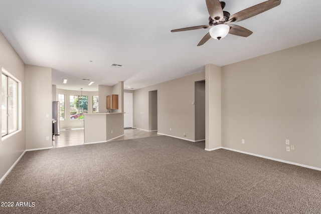 unfurnished living room with baseboards, a ceiling fan, visible vents, and light colored carpet