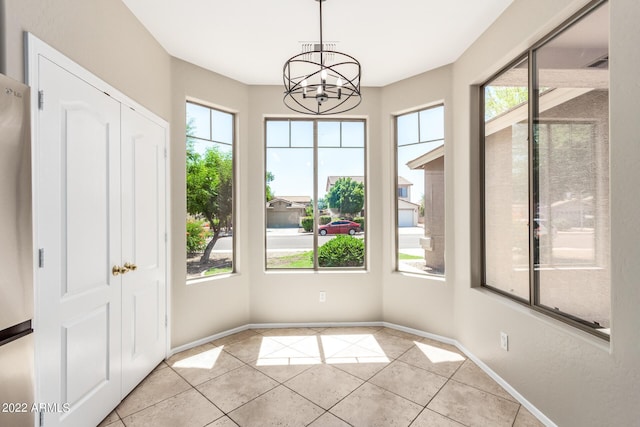 unfurnished dining area with a chandelier, light tile patterned floors, and baseboards