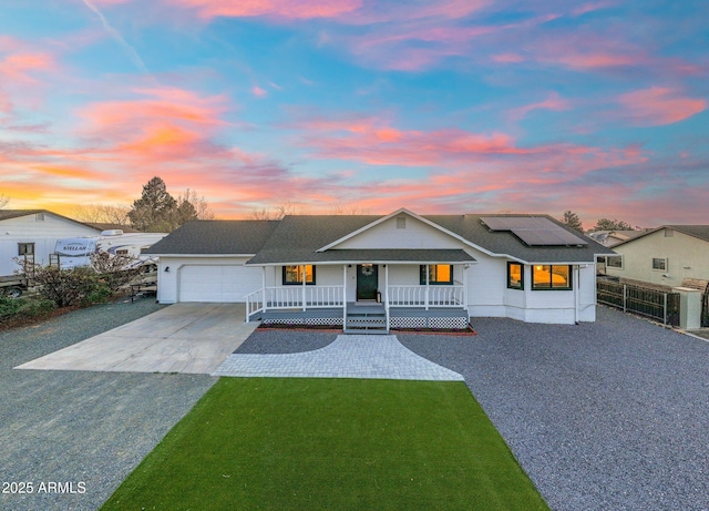 view of front of home with driveway, covered porch, fence, a garage, and a yard