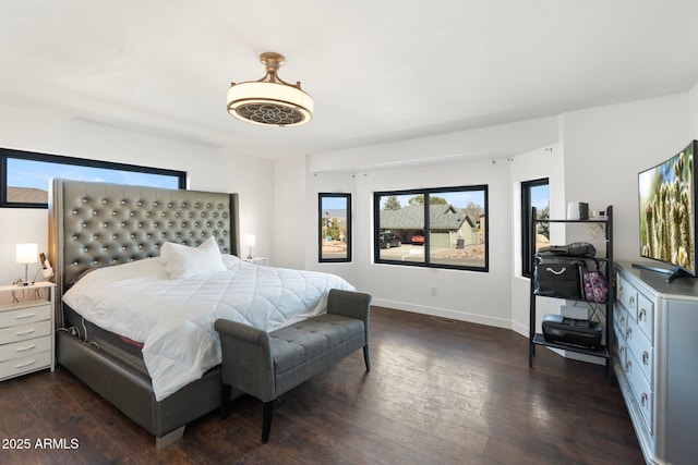 bedroom featuring baseboards, multiple windows, and dark wood finished floors