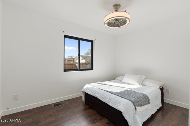 bedroom with baseboards, visible vents, and wood finished floors