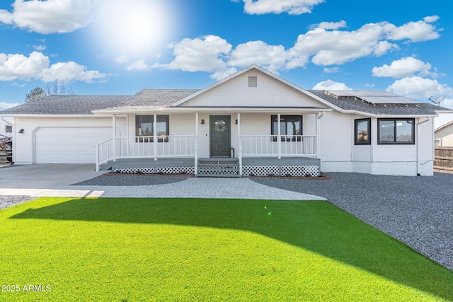 view of front of house with a front yard, concrete driveway, a garage, roof mounted solar panels, and a porch