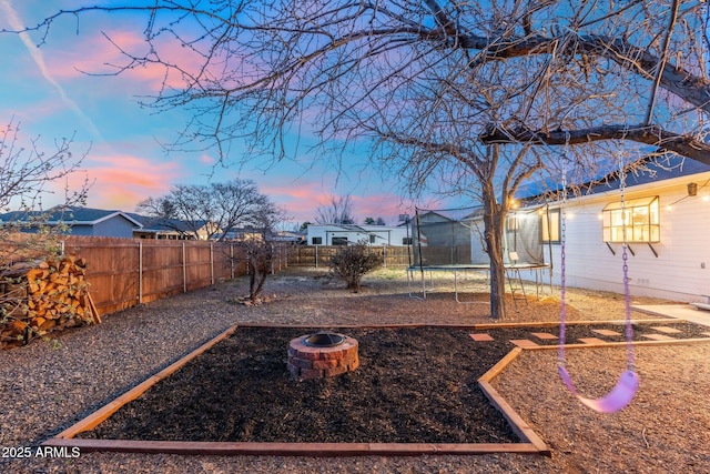view of yard featuring a fenced backyard, an outdoor fire pit, and a trampoline