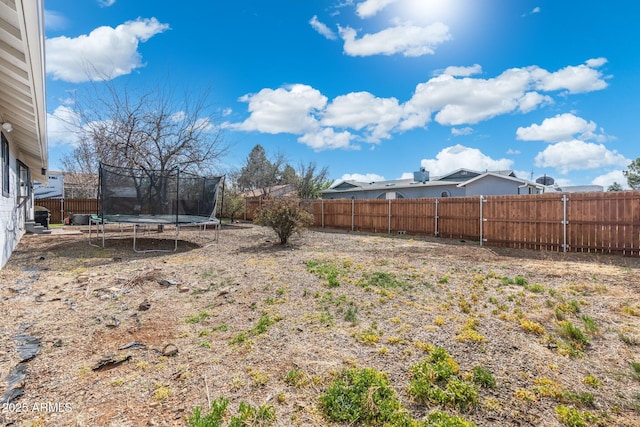 view of yard with a trampoline and a fenced backyard