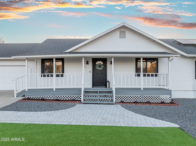 ranch-style house featuring roof with shingles, covered porch, a garage, and concrete driveway
