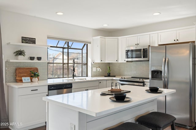 kitchen featuring white cabinets, light countertops, a kitchen bar, appliances with stainless steel finishes, and a sink