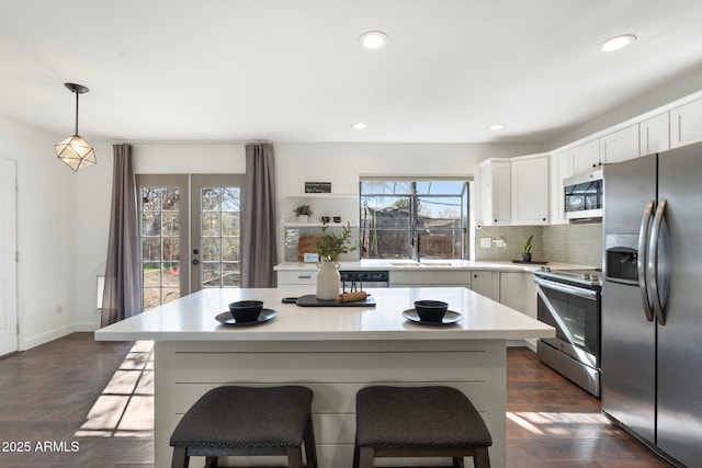 kitchen featuring light countertops, backsplash, a center island, dark wood finished floors, and stainless steel appliances